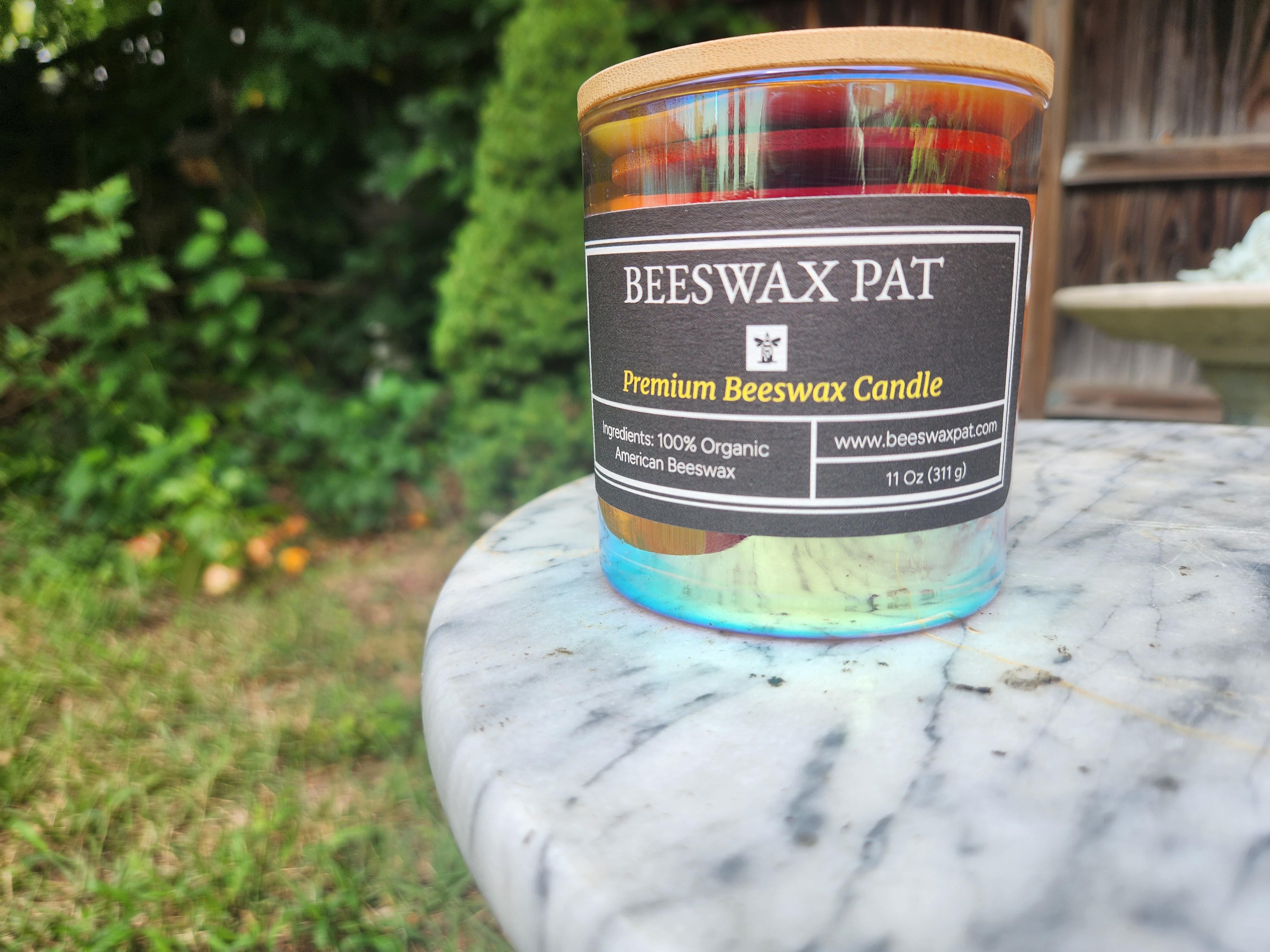 Beeswax Pat candle on a marble table in a garden setting